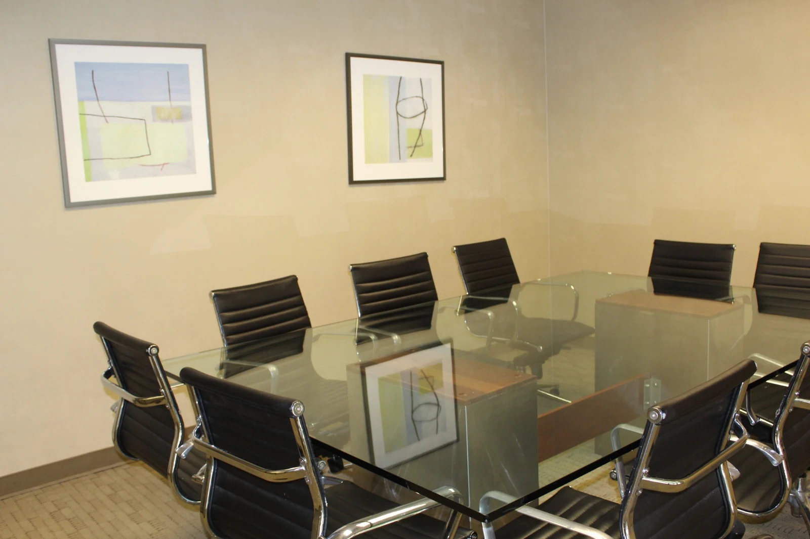Glass meeting table and black chairs beneath framed artwork at Gateway Executive Suites, 500 East E Street
