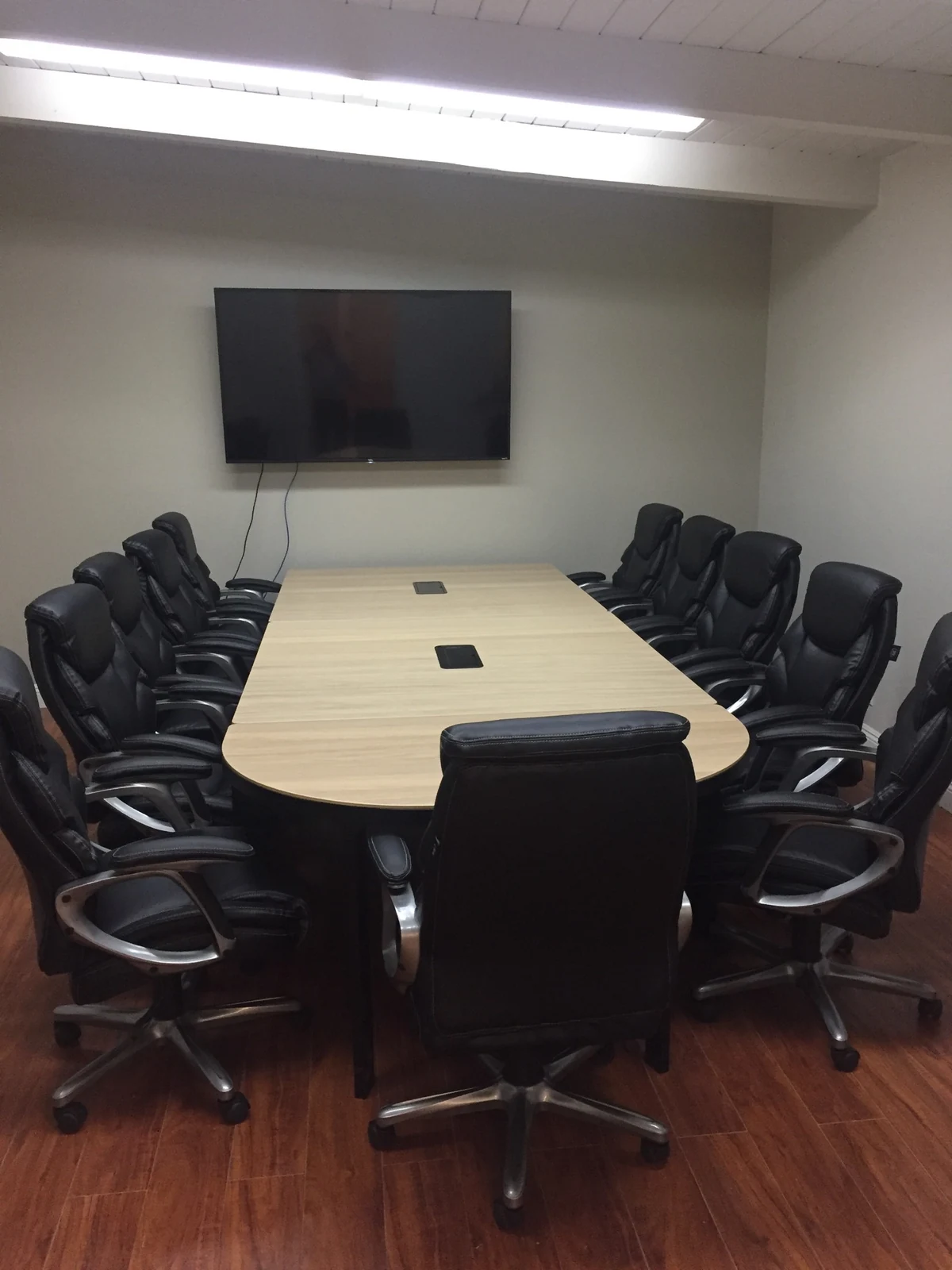 Meeting room at Ontario Executive Suites, 525 N Laurel Avenue with a light wood table, black chairs and wall display